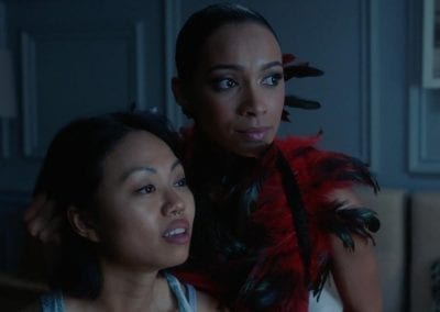 Woman wearing a feather boa holding another woman's head by her hair