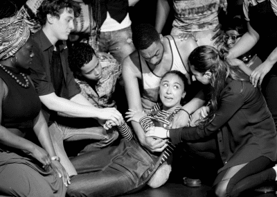 Group of people gathered around a woman who is lying on the floor